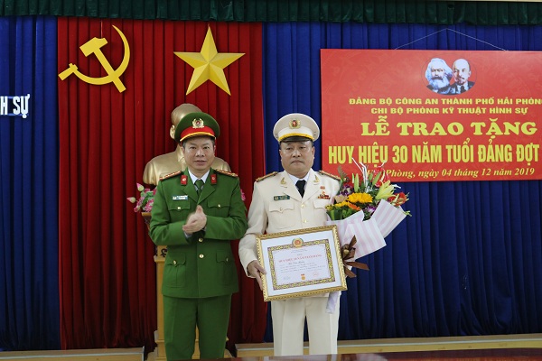Đại tá Lê Nguyên Trường – Phó Giám đốc CATP trao Huy hiệu, tặng hoa chúc mừng Thượng tá Hà Văn Tuấn – Bí thư Chi bộ, Trưởng phòng PC09